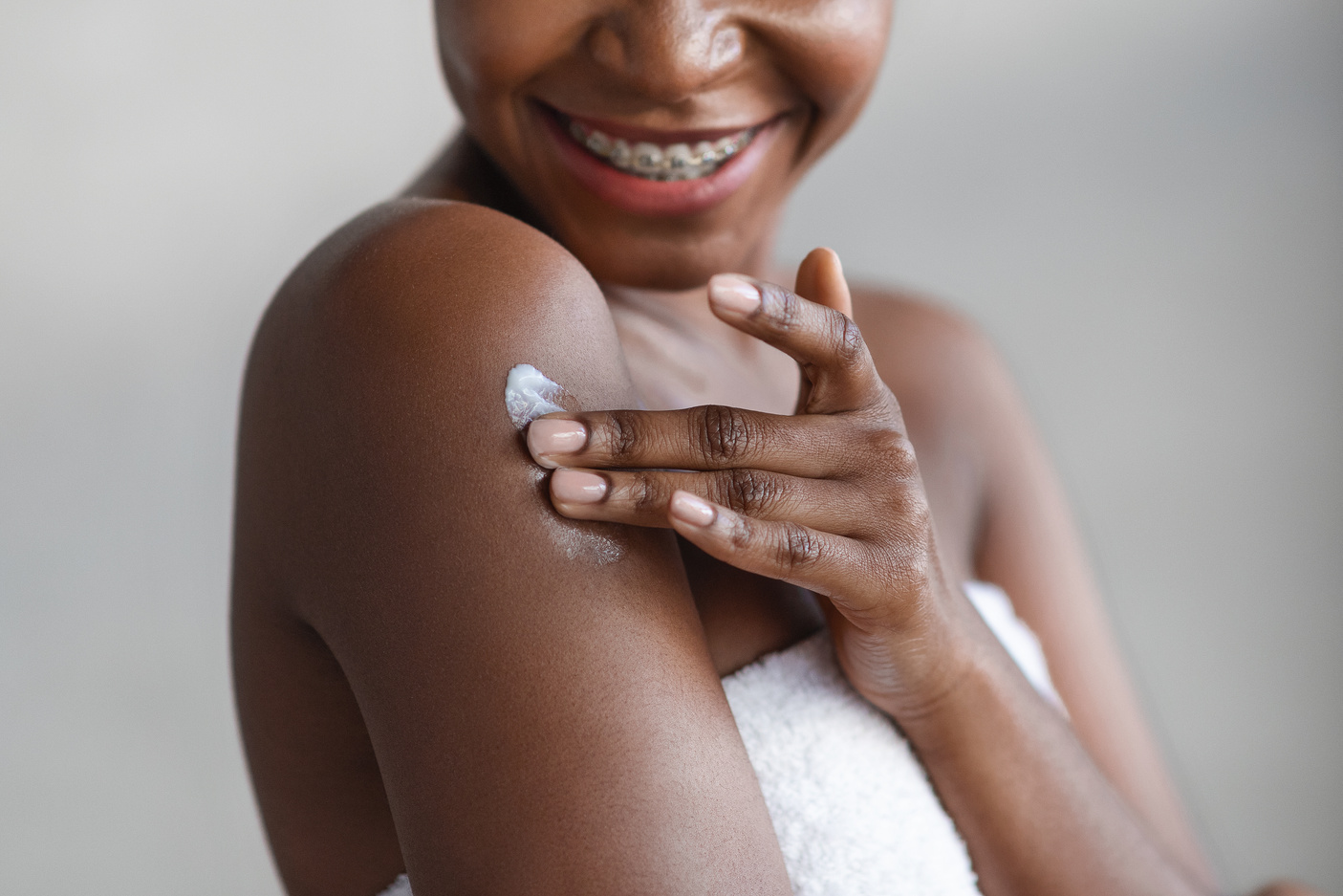 Cropped of black lady using body lotion after